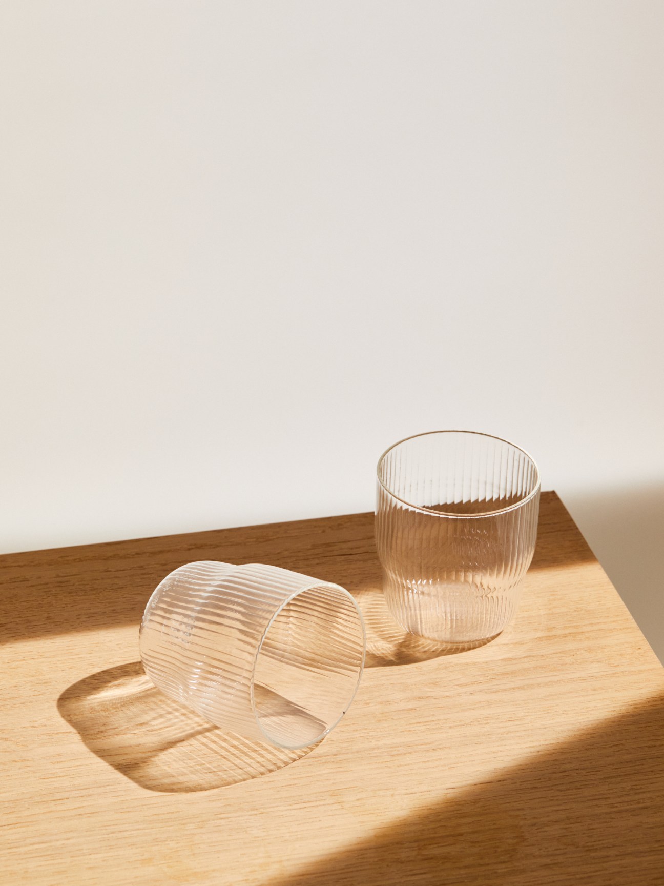 Clear ribbed glass R+D Lab Helg tumblers arranged on wooden surface with natural lighting