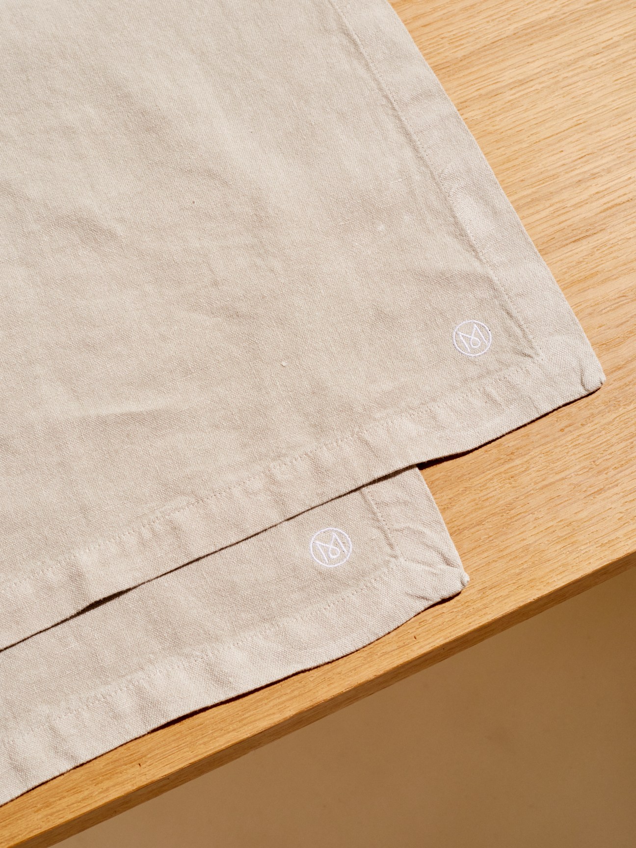 Linen place mats and napkins in warm grey and pine green with embroidered M logo