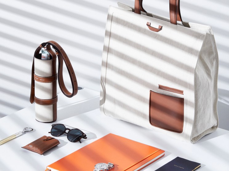 Water bottle holder by Métier, bag by Ermenegildo Zegna, sunglasses by Tod's, and accessories including notebook, pen, watch and key fob arranged on white surface.