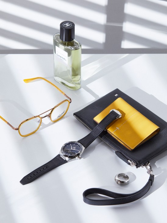 Accessory flatlay with Persol glasses, Chanel fragrance, Omega watch, Bally wallet, Tod's card case and Hermès ring.