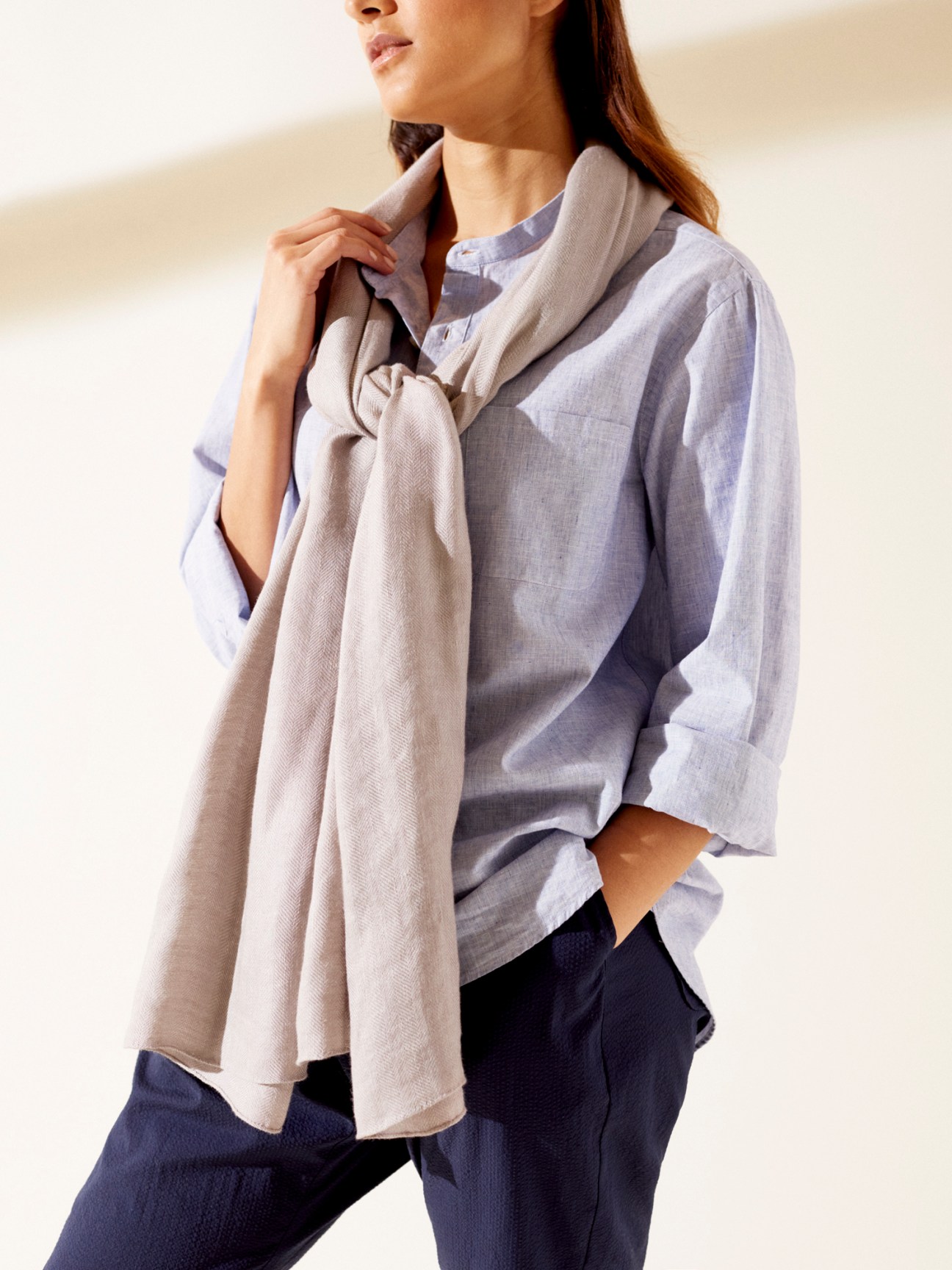 Woman wearing light blue linen shirt with beige bamboo-linen scarf draped around neck