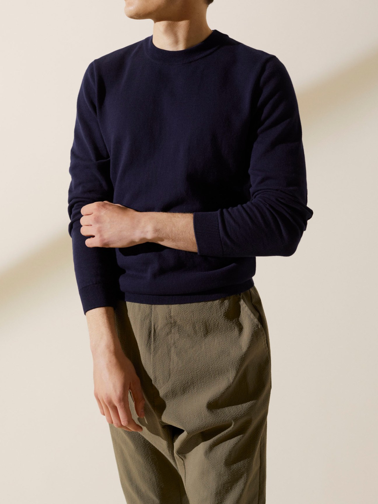 Man wearing navy A Kind of Guise cotton crewneck pullover with khaki trousers