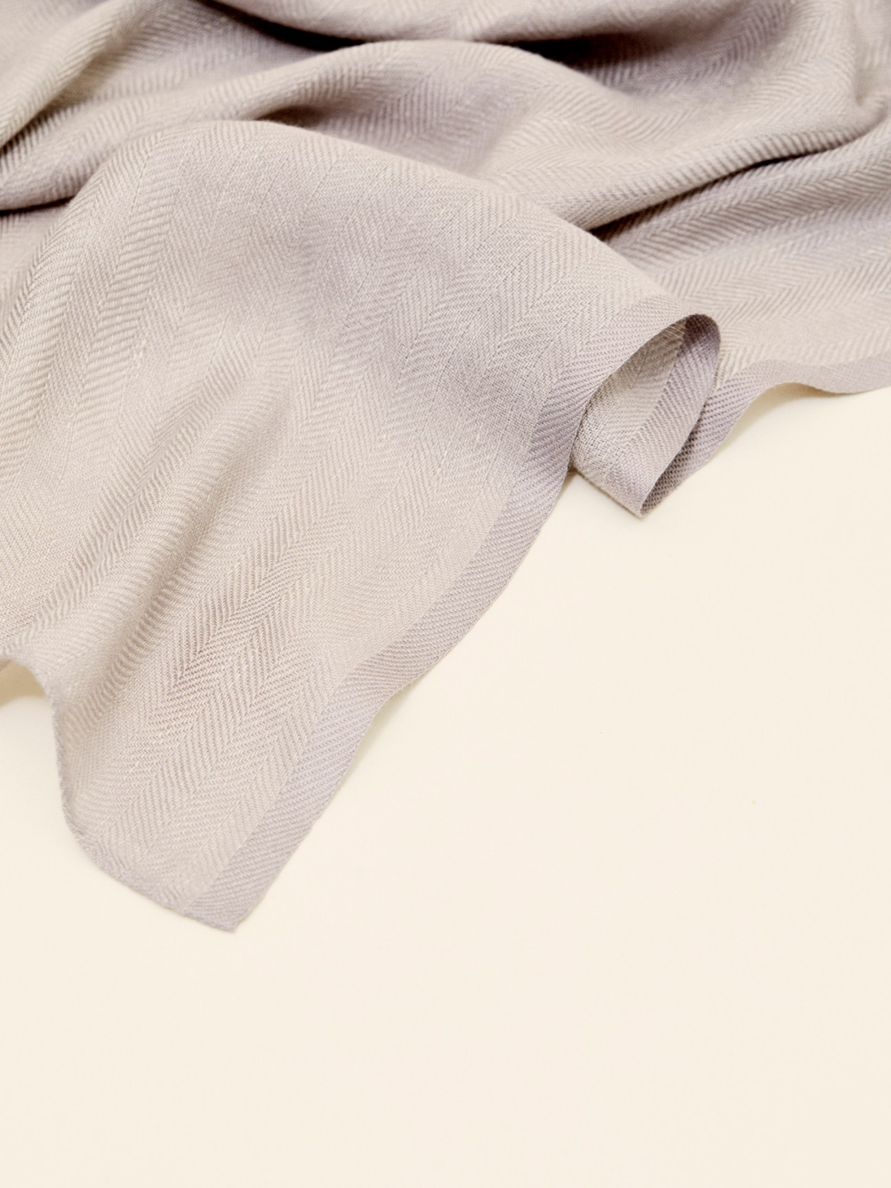 Close-up detail of silvery-grey bamboo-linen scarf fabric showing herringbone weave texture