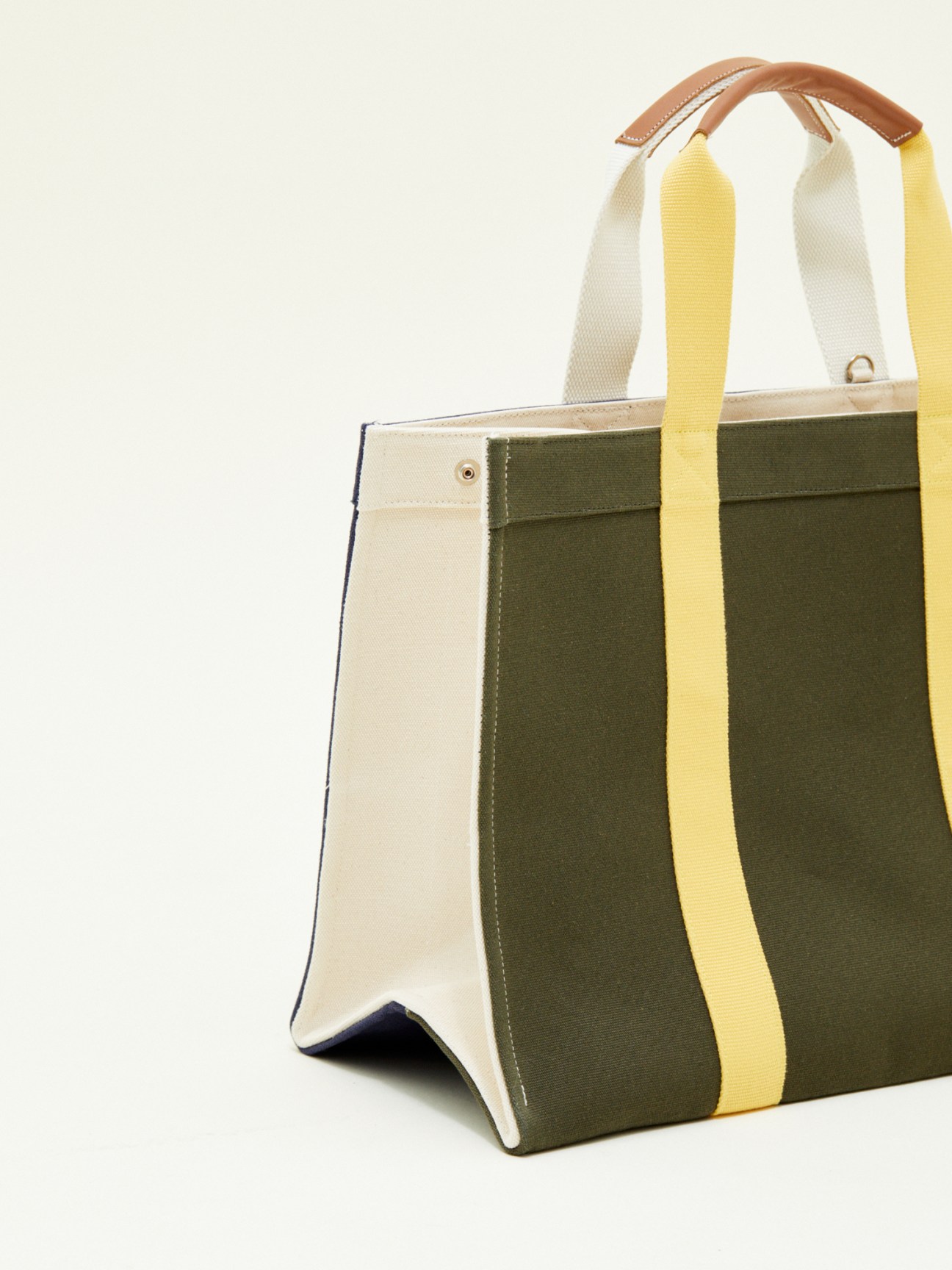Rue de Verneuil x Monocle large tote bag in olive canvas with yellow and white striped handles and brown leather trim.