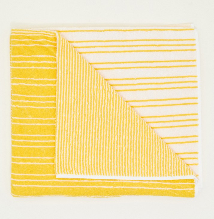 Monocle beach towel in canary yellow with white horizontal stripes and textured terrycloth weave.