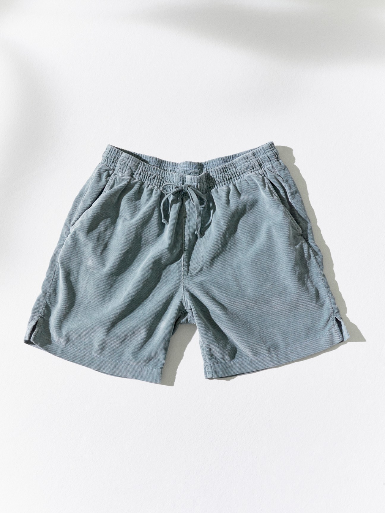 Light blue drawstring shorts with elastic waistband and relaxed fit laid flat against white background