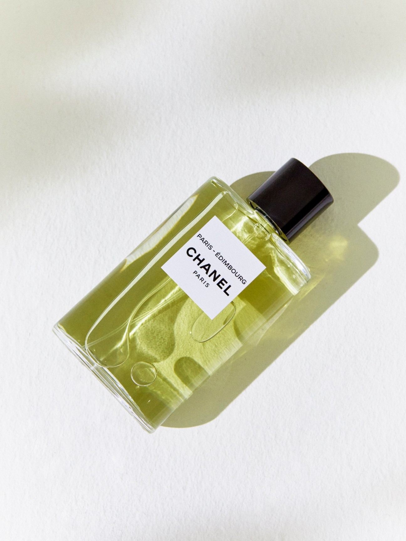 Green tinted glass perfume bottle with black cap and white Chanel Paris-Édimbourg label