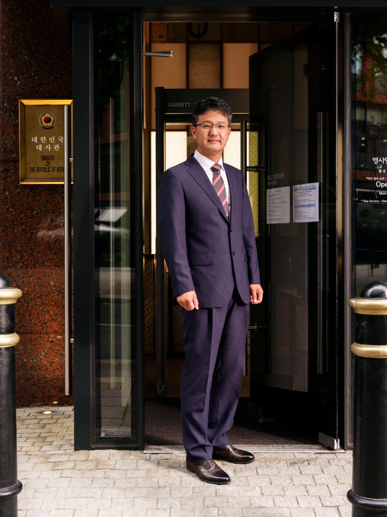 Moon Sangmin, South Korean commercial attaché, standing in doorway of embassy building wearing dark suit