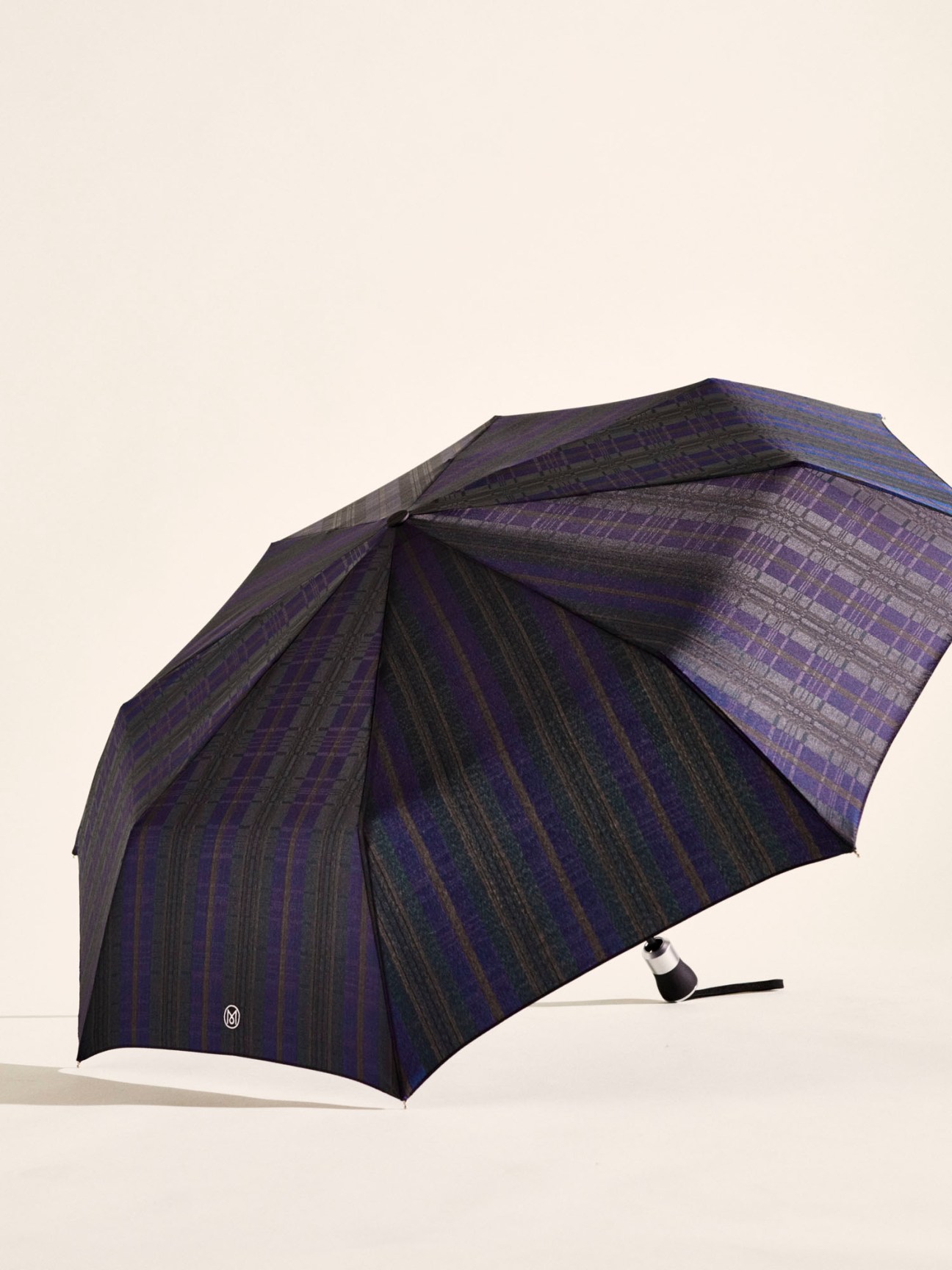 Dark blue and purple plaid umbrella with black handle against beige background
