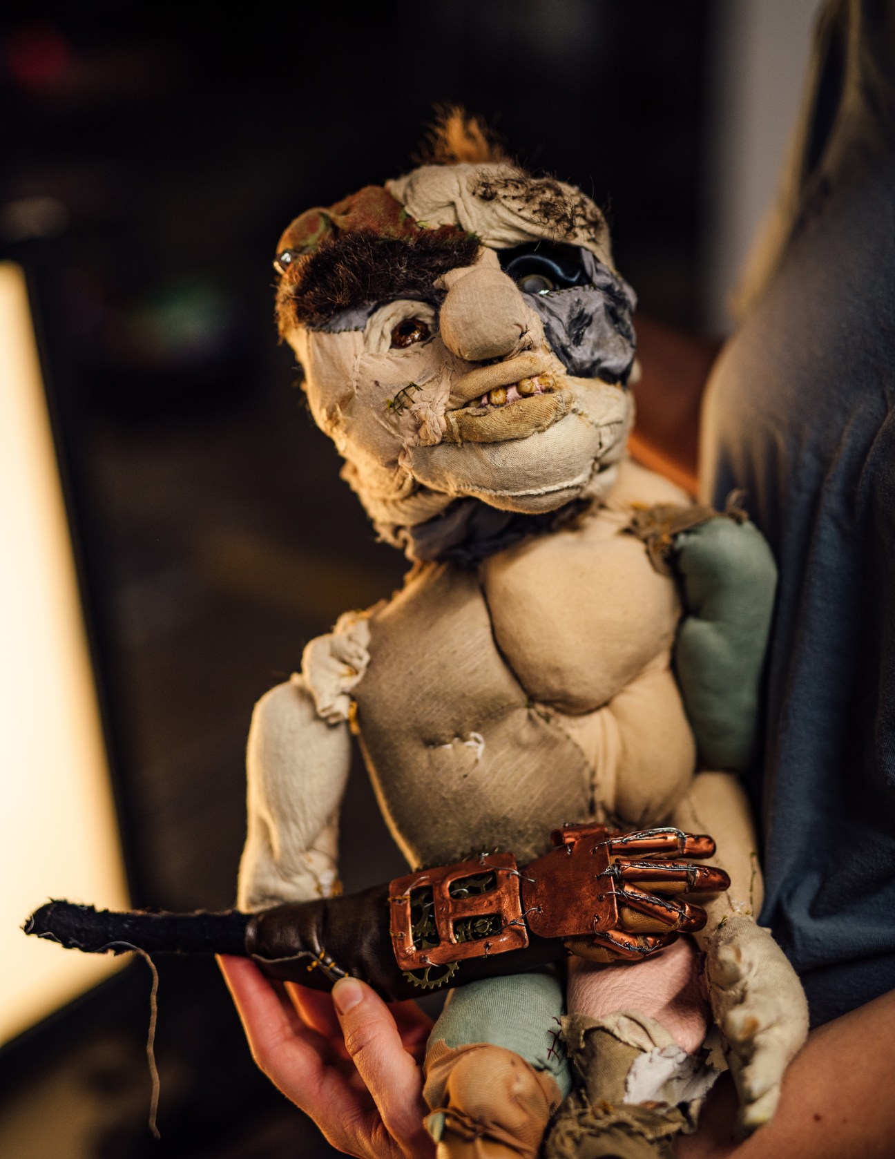 Handmade puppet figure with fabric construction and leather belt held in someone's hands