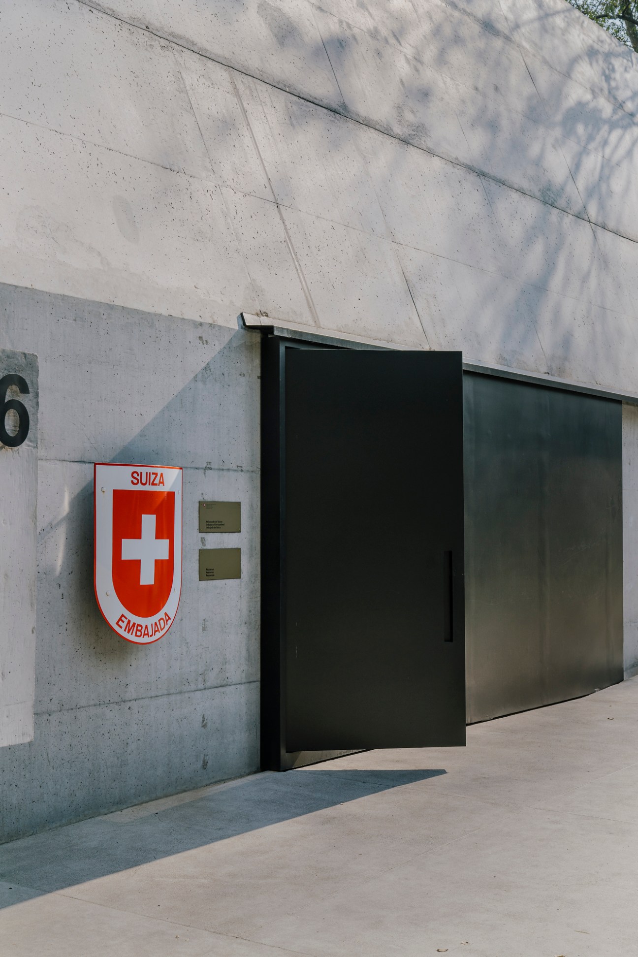 Interior reception area of Swiss ambassador residence featuring modern minimalist design with concrete walls and artwork