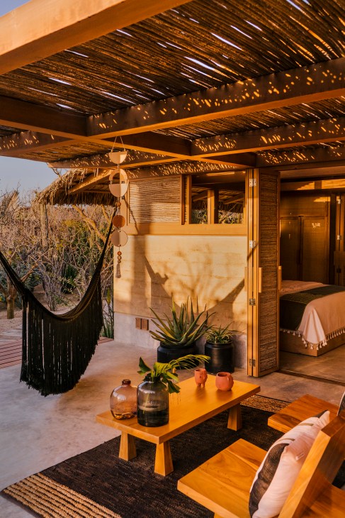 El Perdido hotel jacal in El Pescadero with woven pergola, hammock, wooden furniture and desert views.