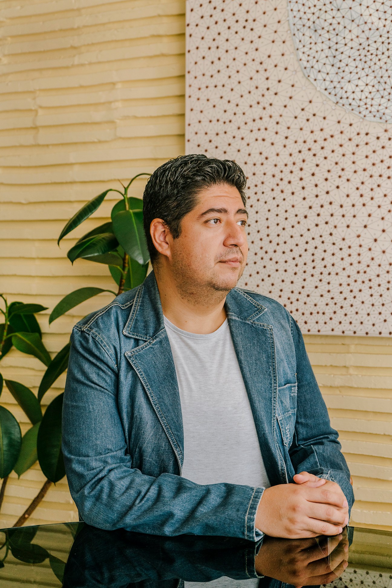 Alejandro, Casa Pani's house manager, sits looking to the side wearing a denim jacket
