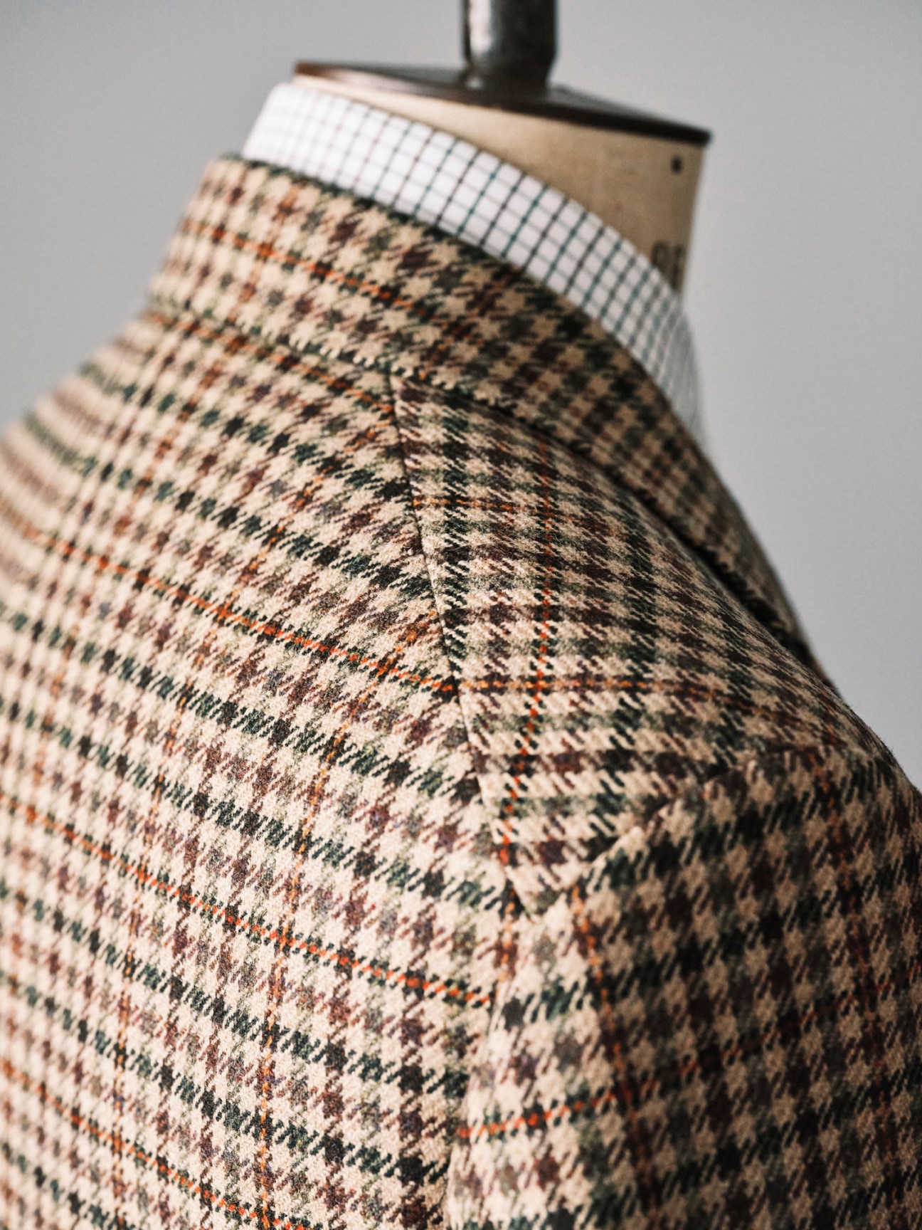 Close-up detail of a patterned tweed blazer showing intricate woven fabric texture and construction