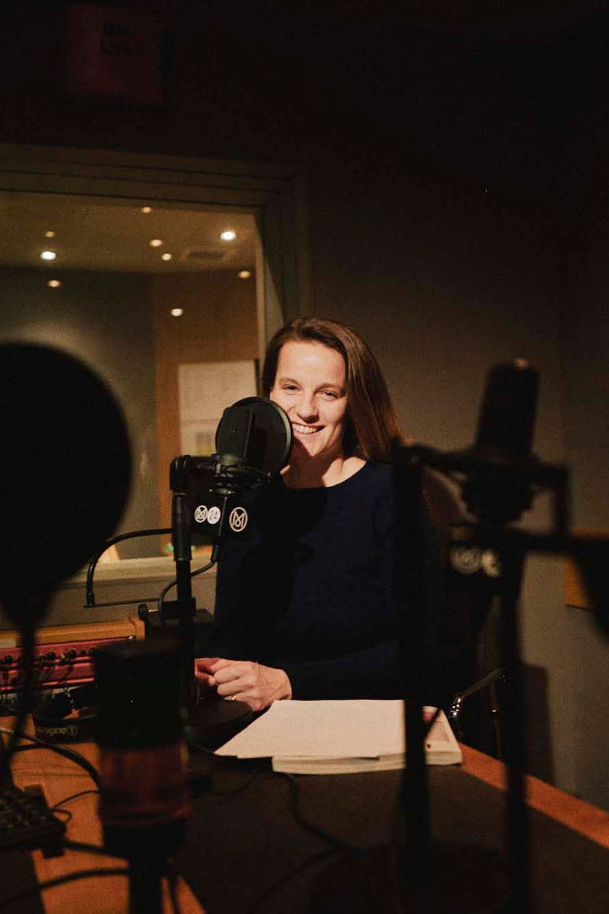 Woman smiling while speaking into a professional microphone in a radio studio