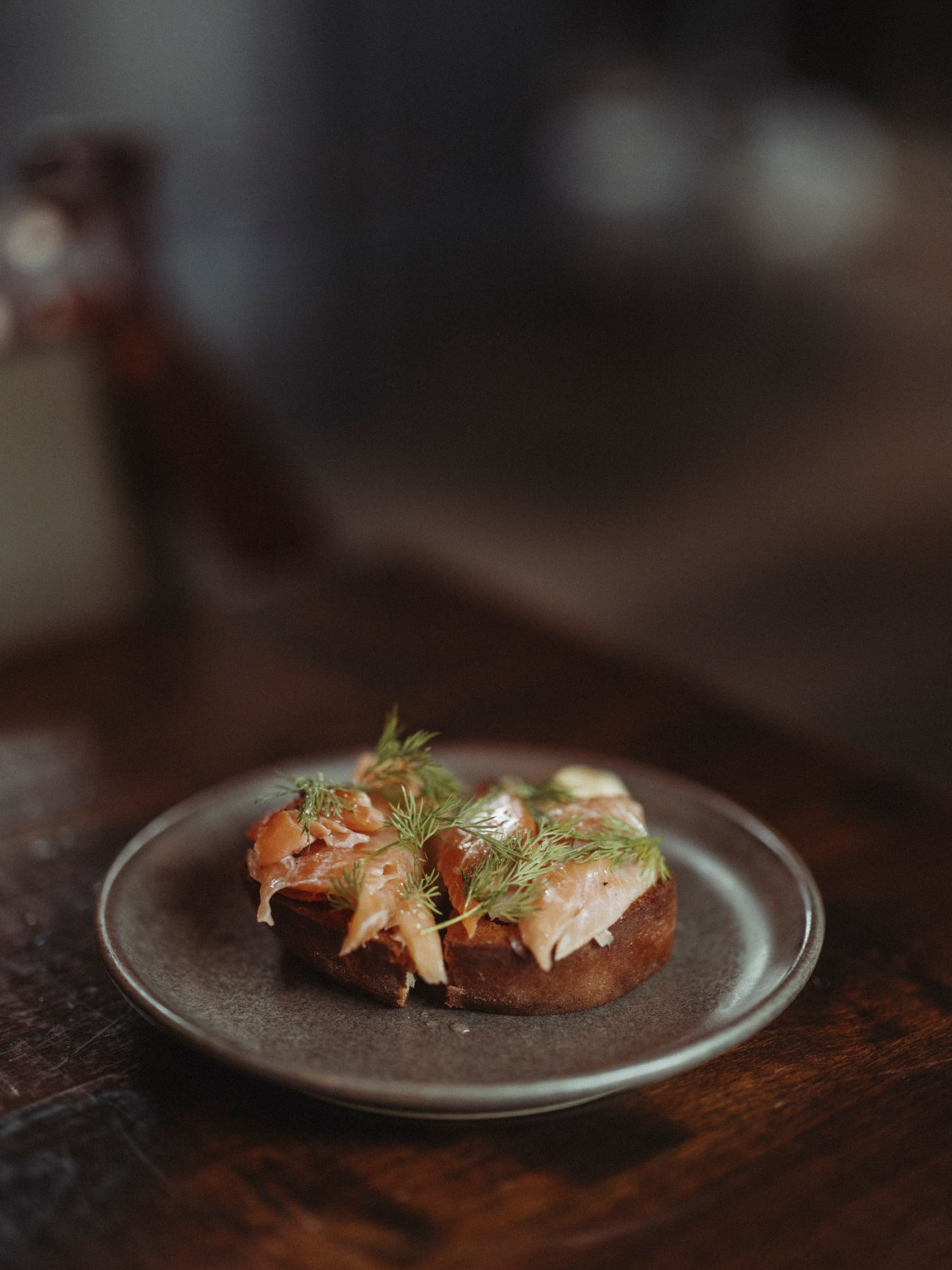 Open-faced sandwich with smoked fish, herbs and cream on dark bread served on ceramic plate