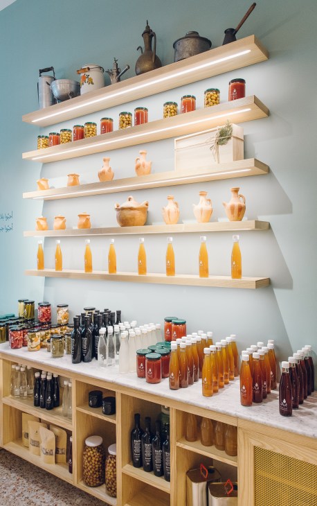 Interior of Feryal shop with wooden shelves displaying jars of local Lebanese products including oils, preserves and ceramics.