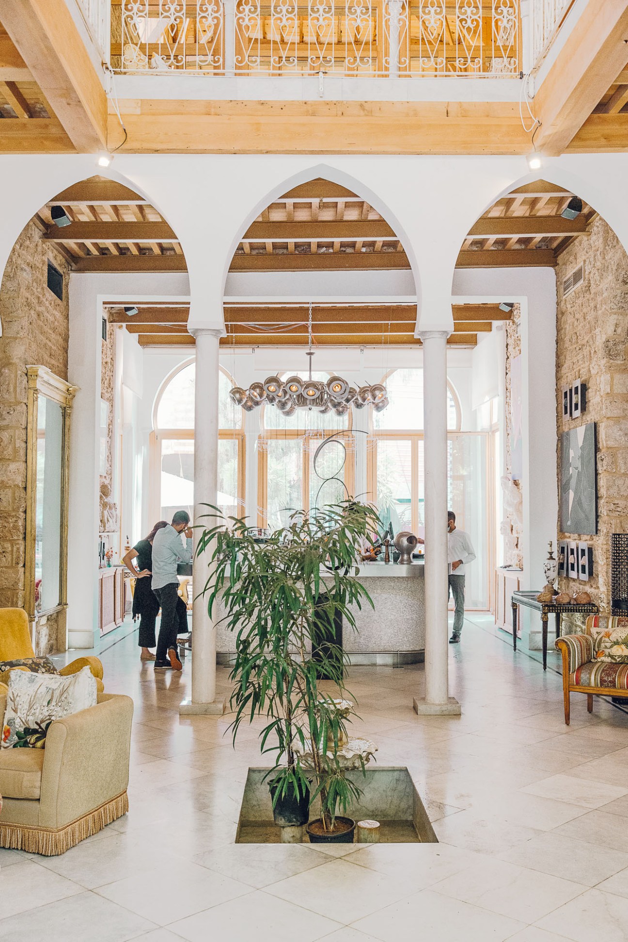 Arthaus hotel lobby with arched ceilings, wooden beams, potted plant, and vintage furnishings.