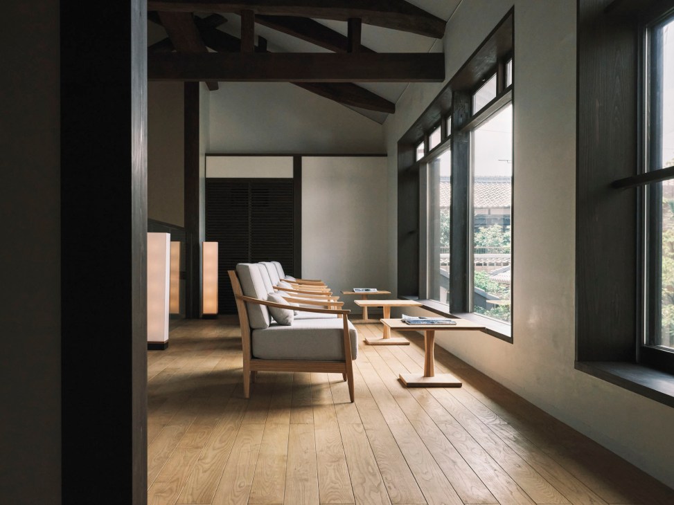 Modern Japanese interior lounge area with wooden floors, exposed beams, and traditional seating by large windows