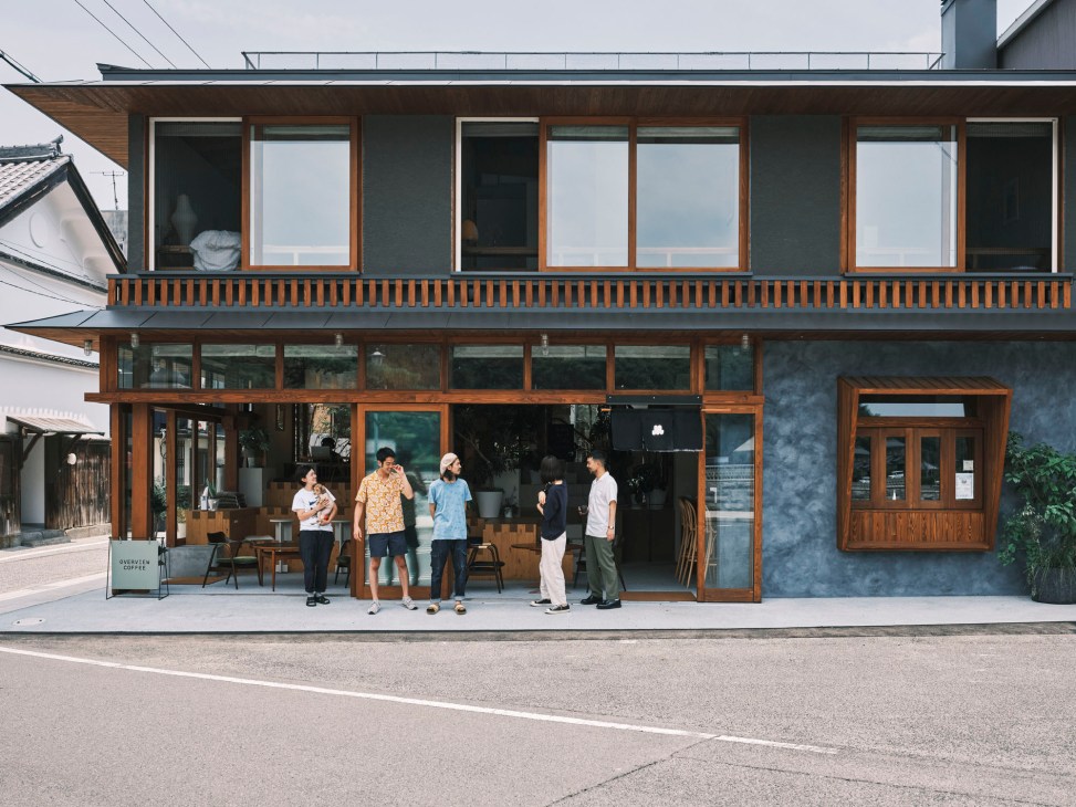 Modern waterfront café and workspace building with people gathering outside