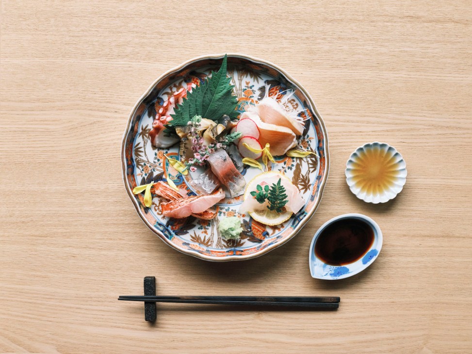 Fresh sashimi platter with various types of raw fish artfully arranged on decorative Japanese porcelain