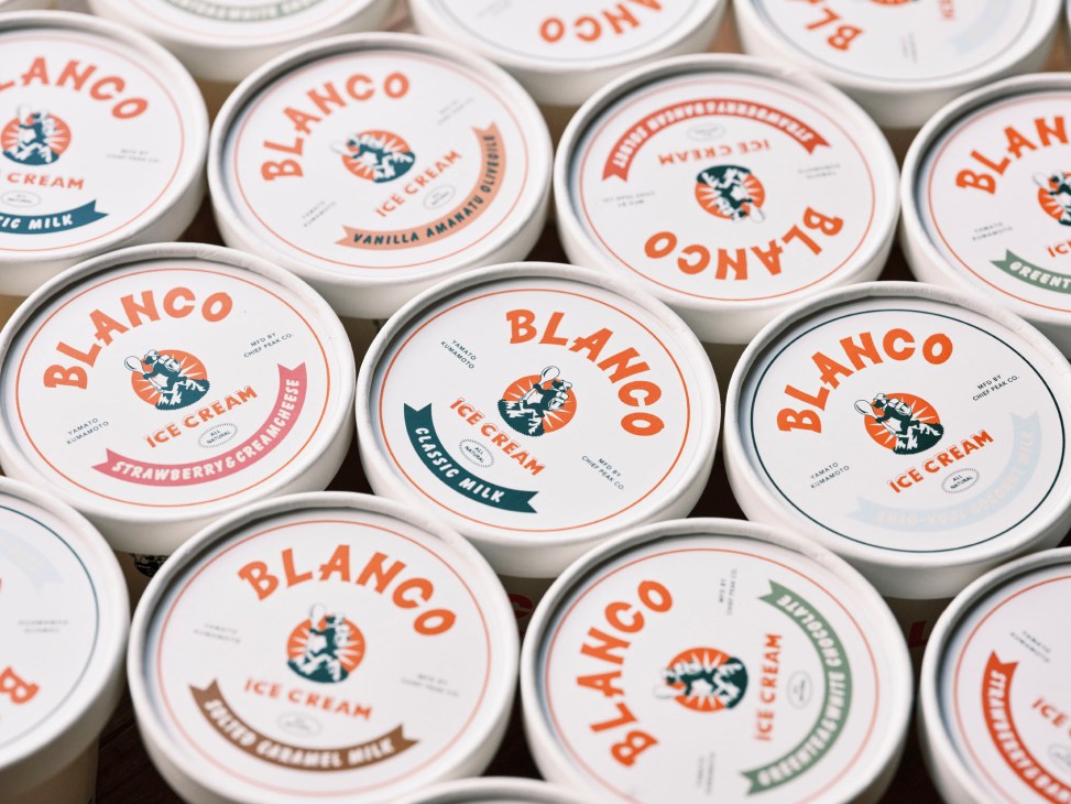 Multiple containers of Blanco ice cream with white lids and orange branding arranged closely together