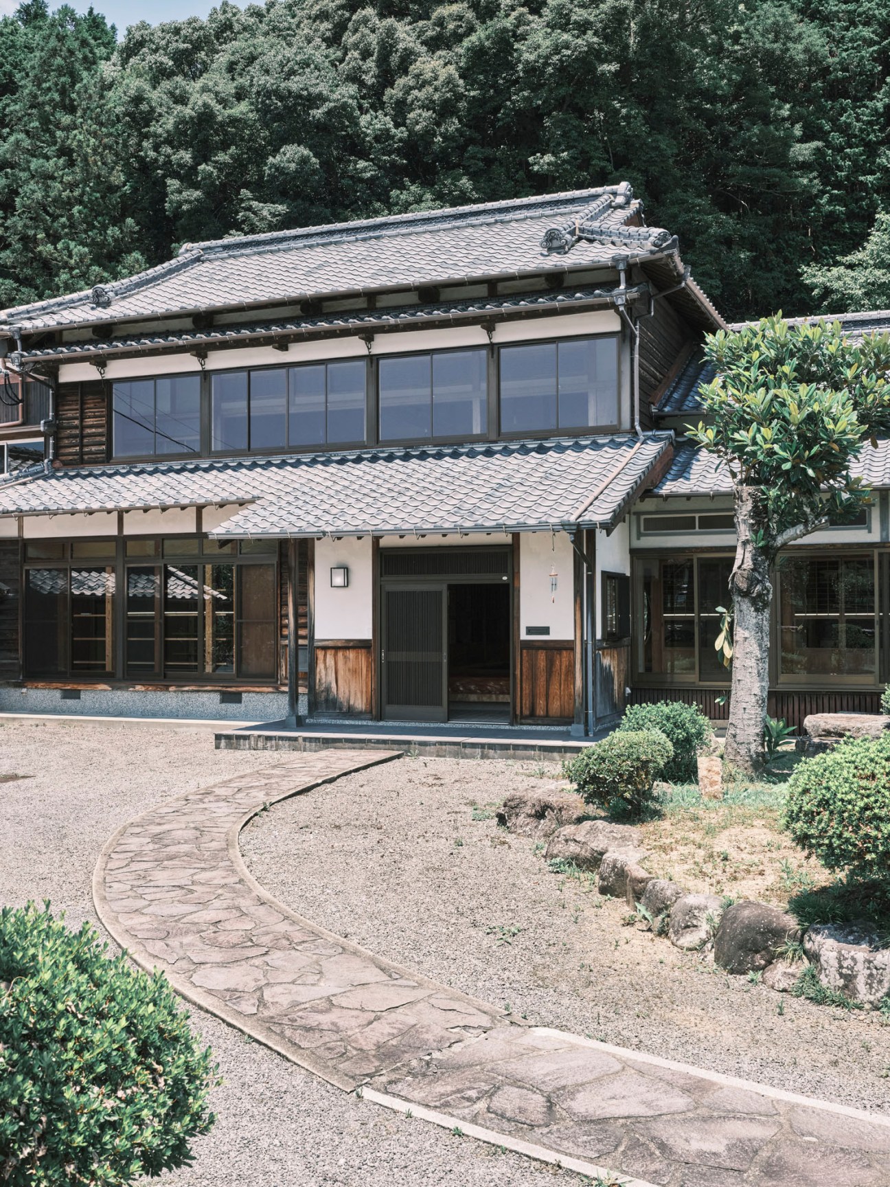 Traditional Japanese house interior with tatami mats, wooden beams, and large windows showing natural light