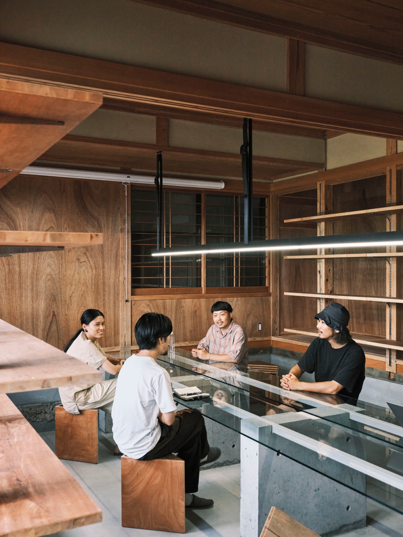 Four people sitting around a long glass table in a renovated traditional Japanese house office space