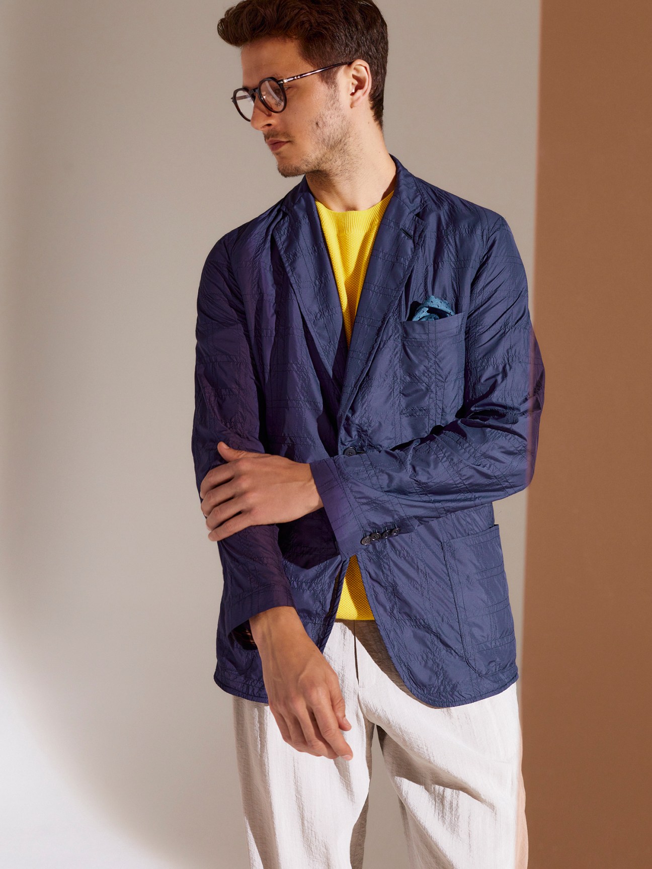 Man wearing navy Brioni blazer with yellow jumper and light trousers