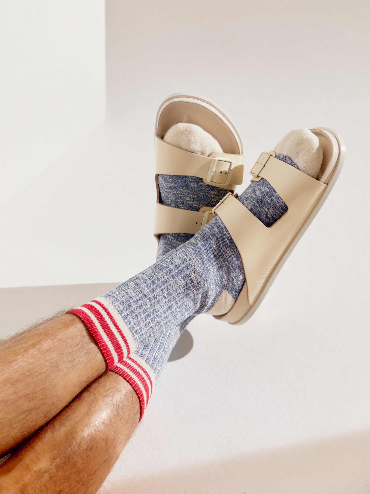Gray ribbed socks with red and white striped cuffs worn with beige Birkenstock sandals