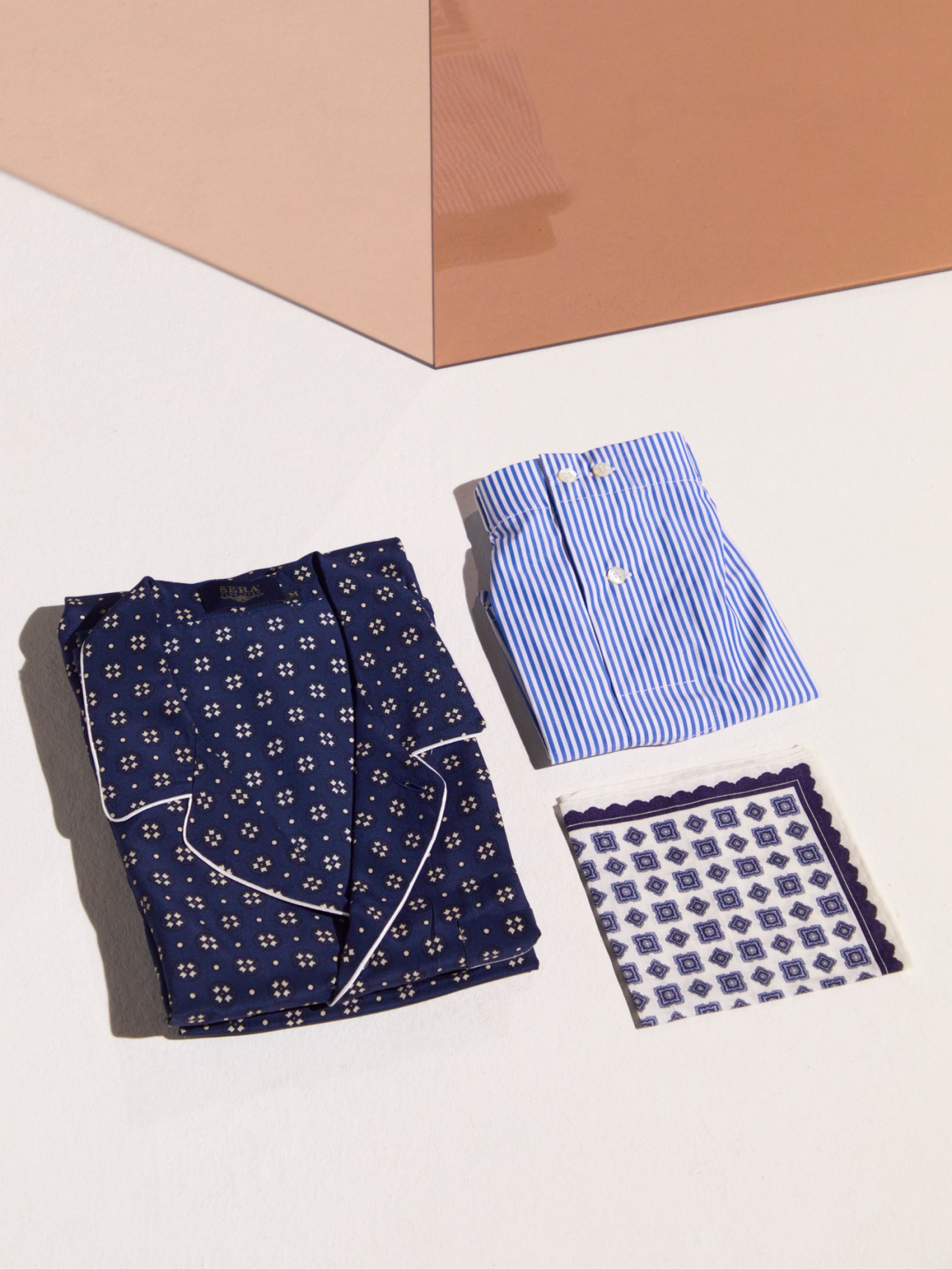 Folded silk pajamas, pocket square, and accessories with geometric patterns showcasing Serà Fine Silk Italian craftsmanship