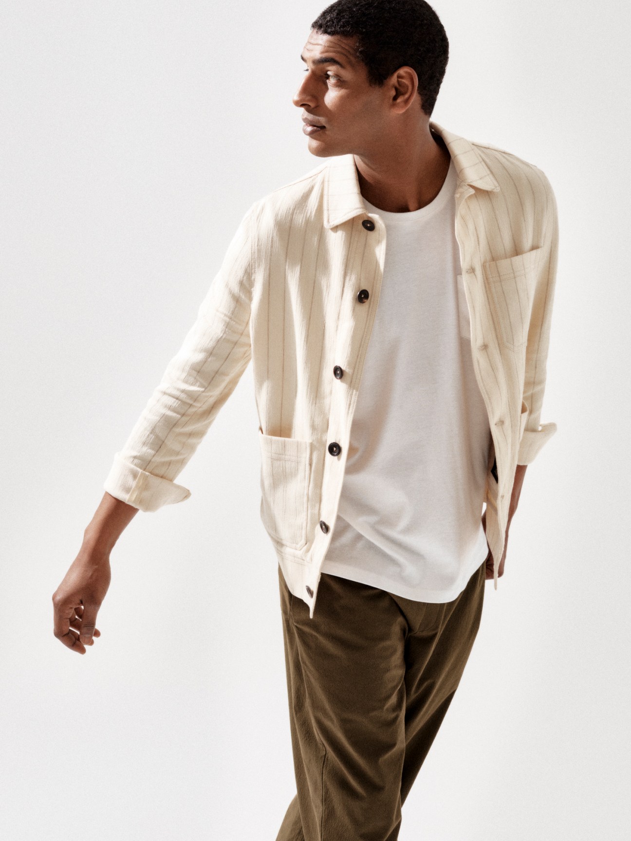 Model in cream striped jacket with white t-shirt and olive trousers