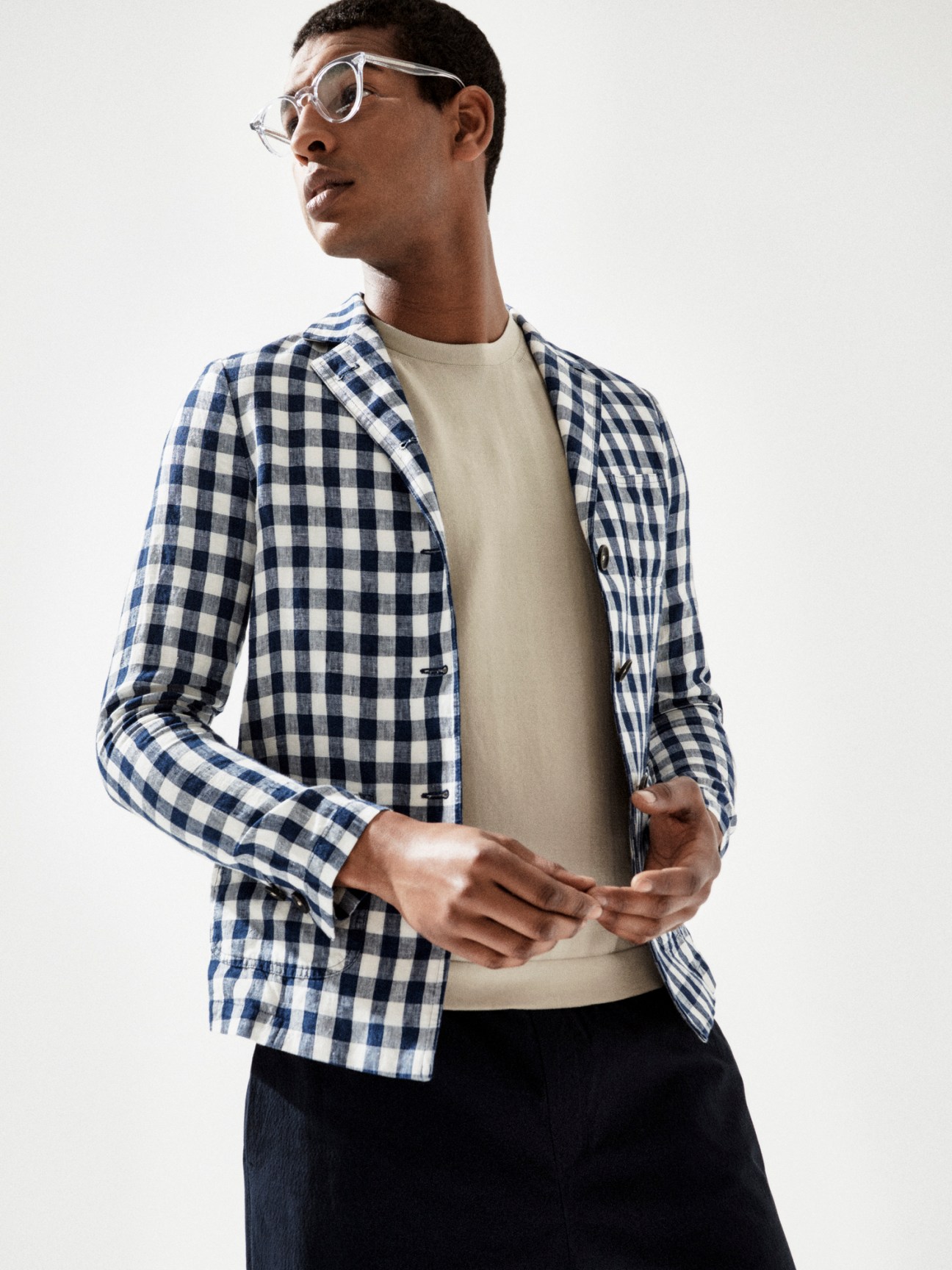 Model wearing brown checked jacket with cream jumper and dark shorts