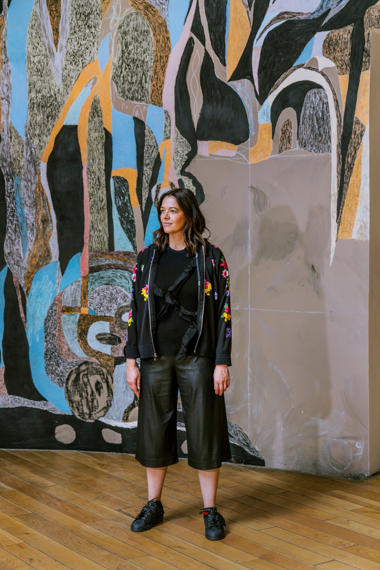 Woman standing in front of colorful abstract mural artwork inside Lago gallery in Mexico City.