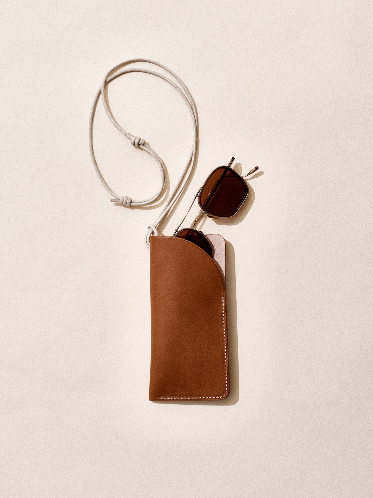 Brown leather glasses case with strap and tortoiseshell sunglasses