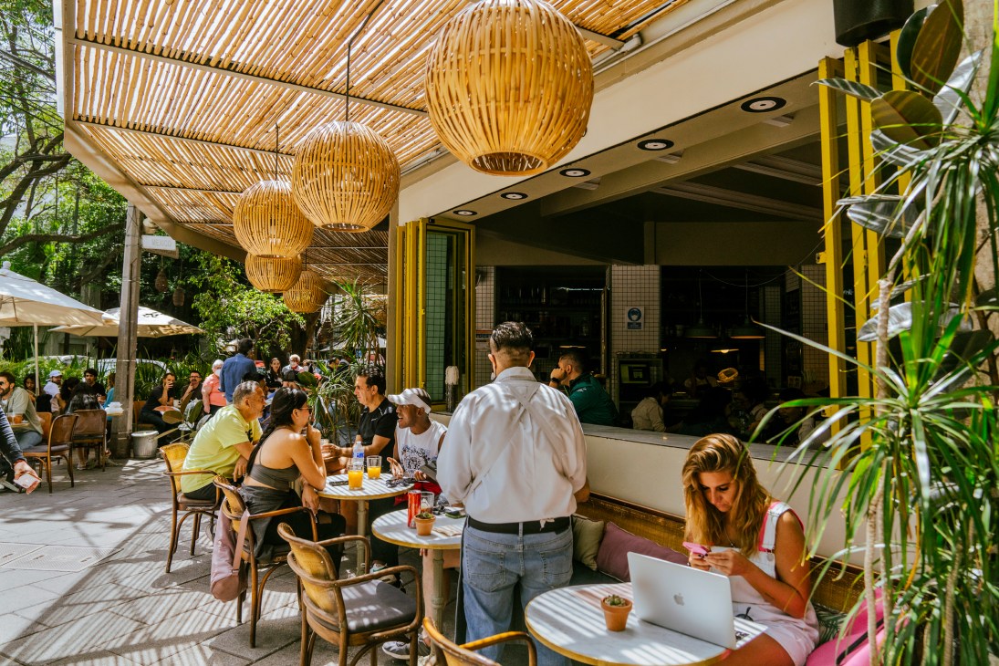 Tree-lined street in Condesa with outdoor restaurant seating and people dining