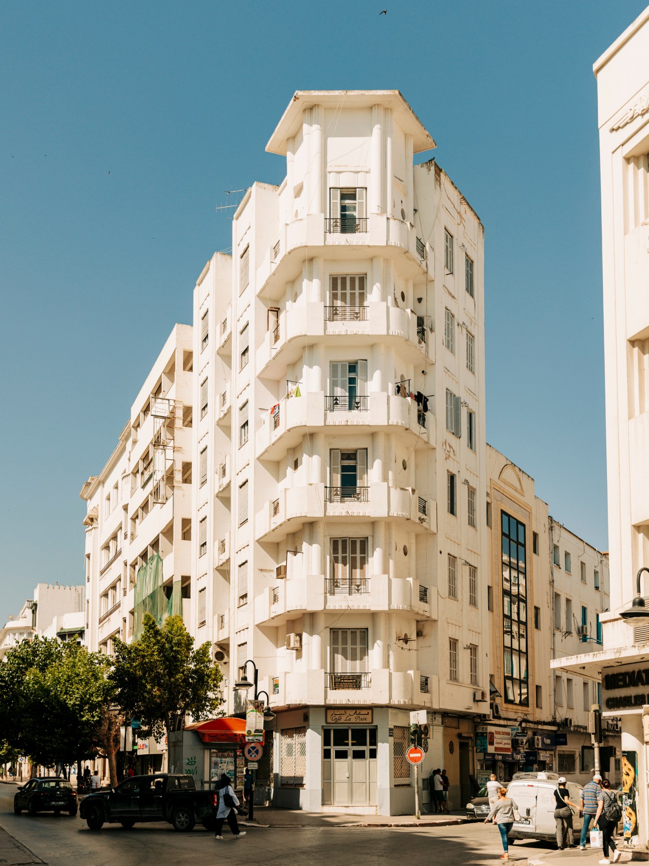 White art deco residential building with curved balconies and geometric details on a street corner in Tunis