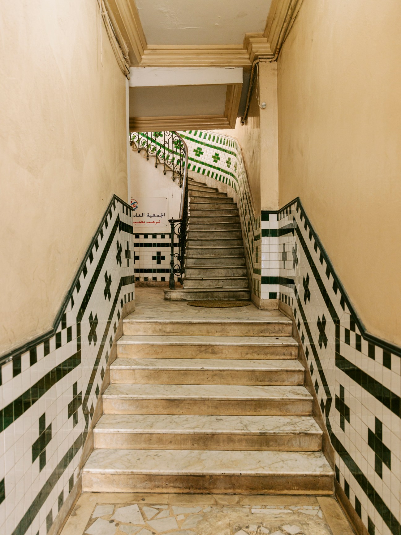 Stone staircase with geometric green and white tile pattern in historic Tunisian building interior