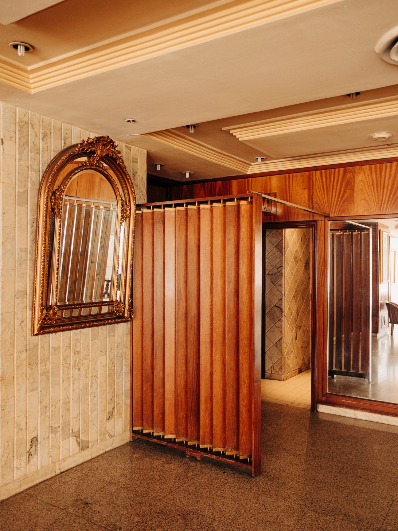 Interior of El Hana International hotel lobby with wood paneling, ornate mirror, and modernist design elements