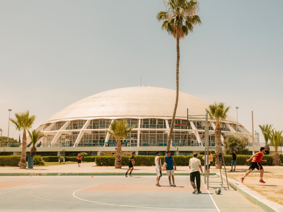El Menzah Sports Palace with its distinctive white domed roof and modern architecture, palm trees in foreground