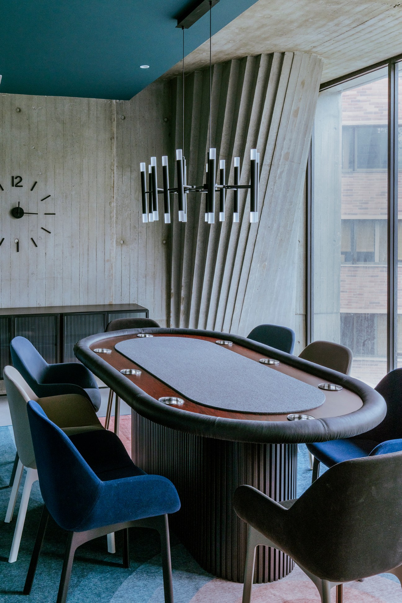 Modern poker table with leather chairs in concrete interior space inside Iqon building