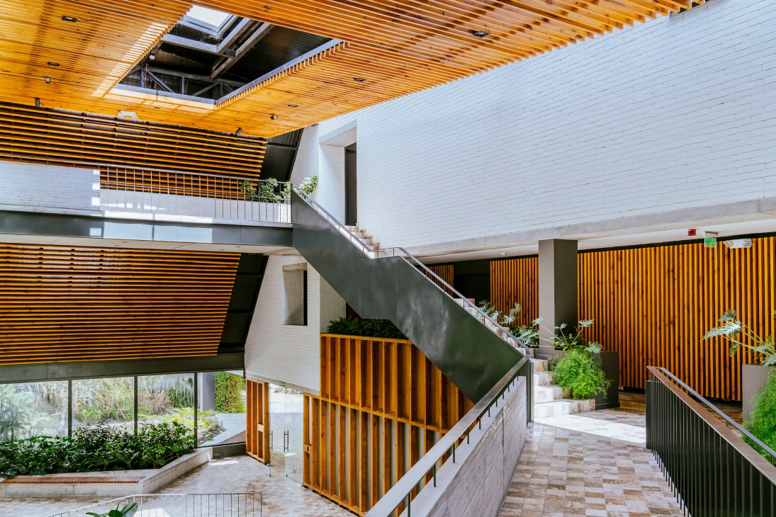 Multi-level interior with wooden slat ceiling, concrete stairs, white brick walls and integrated planters