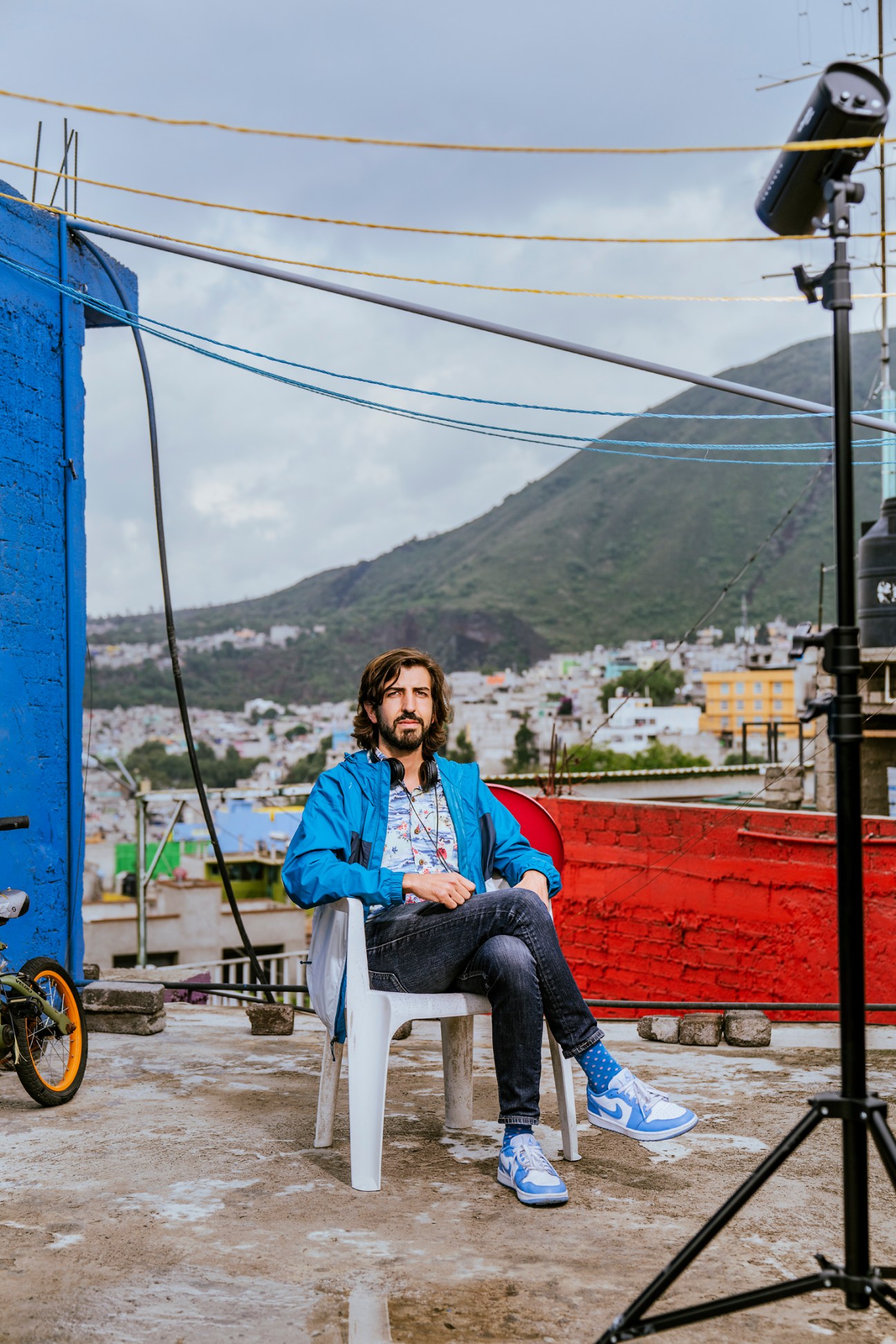 Director Santiago Limón sitting on a white chair on an outdoor rooftop terrace with colorful buildings in background