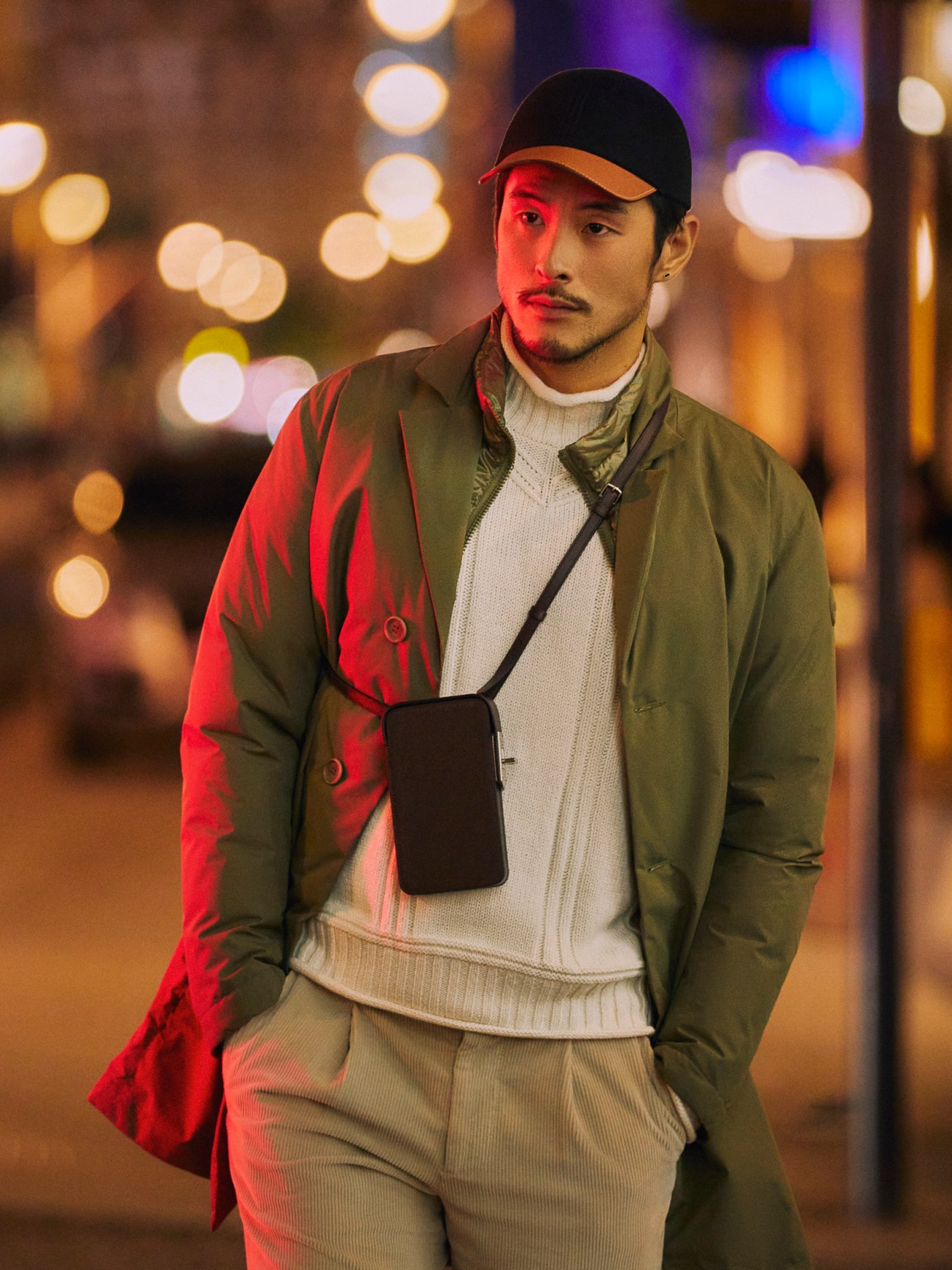 Man in dark coat and cap carrying a bag