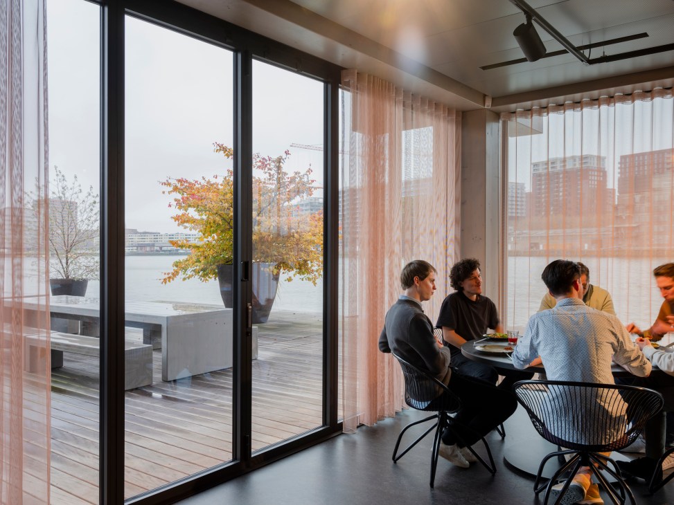 Meeting in progress around table with harbour views through floor-to-ceiling windows at Floating Office Rotterdam