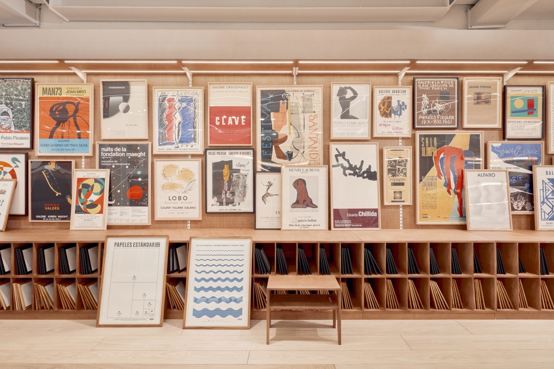 Interior of La Papelería pop-up shop with organized wooden shelving displaying art posters, prints, and paper products