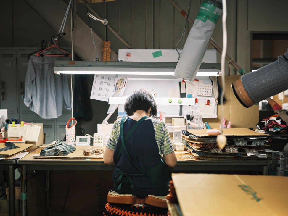 Close-up of hands performing detailed handwork on socks in a manufacturing facility