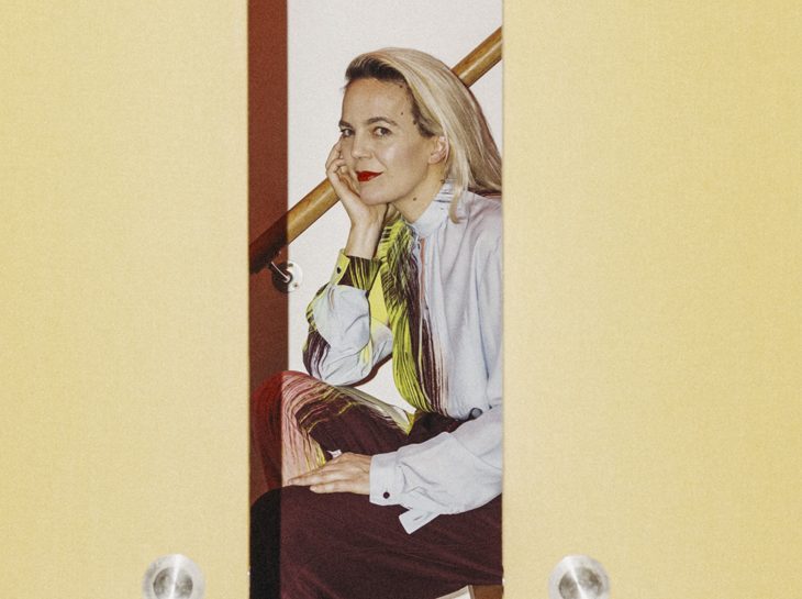 Frith Kerr sitting in her west London studio surrounded by books on shelves, wearing a dark top and looking thoughtfully