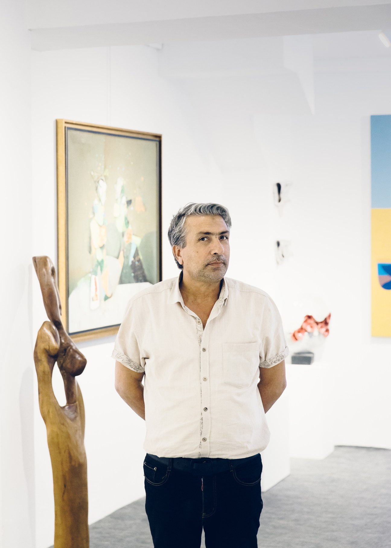 Art dealer Haider Hashem el Mussawi standing in white gallery space with framed artwork on walls