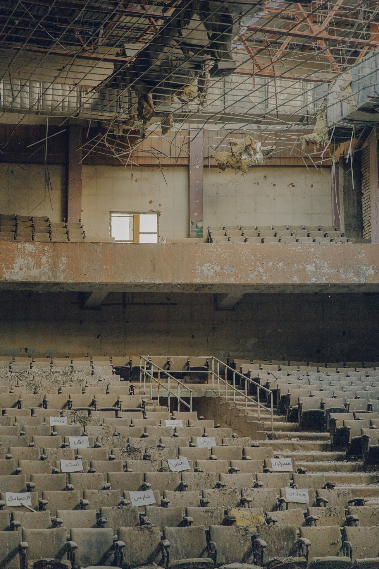 Damaged theater interior with rows of seats and debris from damaged ceiling and exposed metal framework